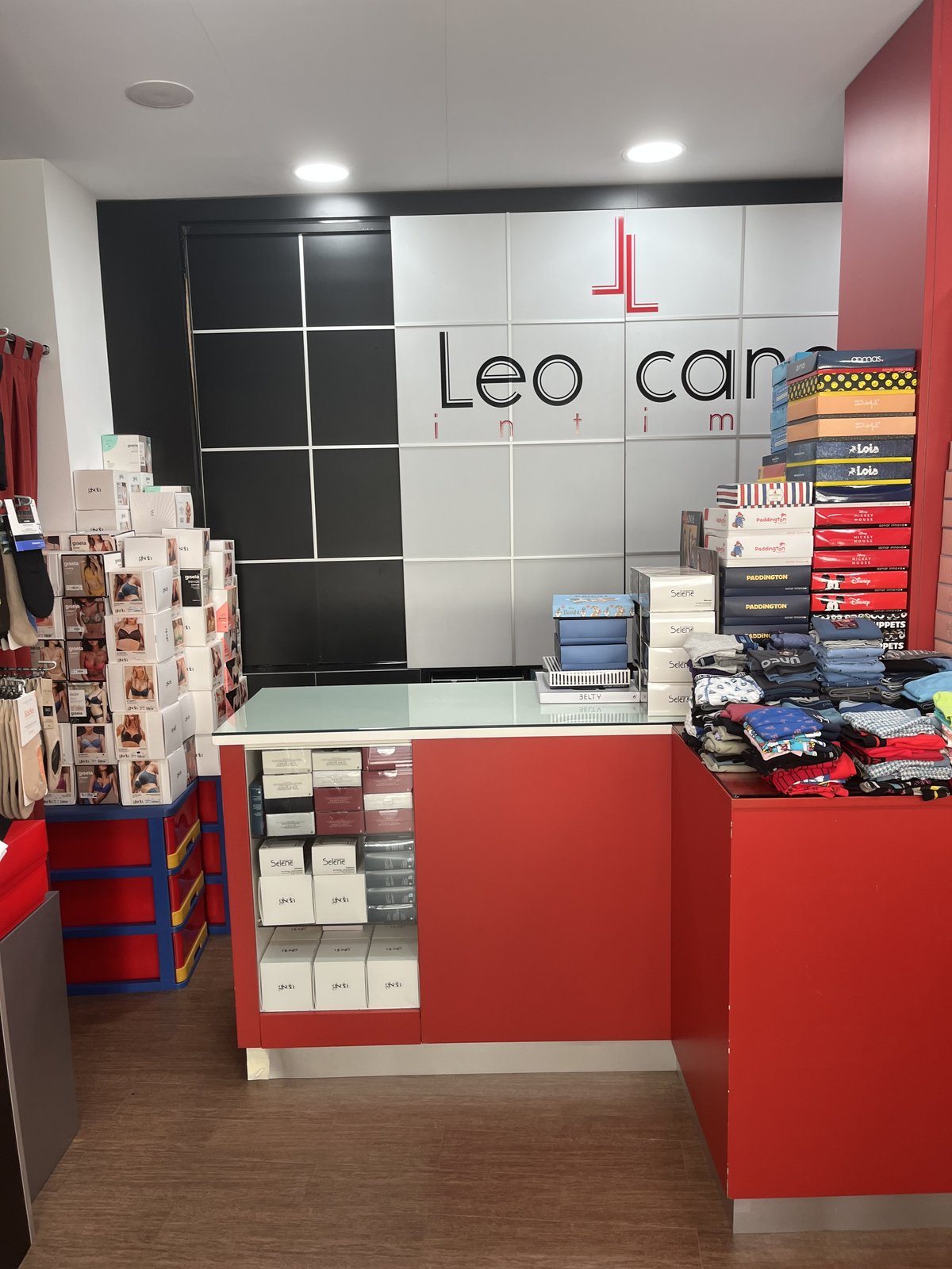 Interior de la tienda con mostrador rojo, calcetines y cajas de homewear Aznar Innova